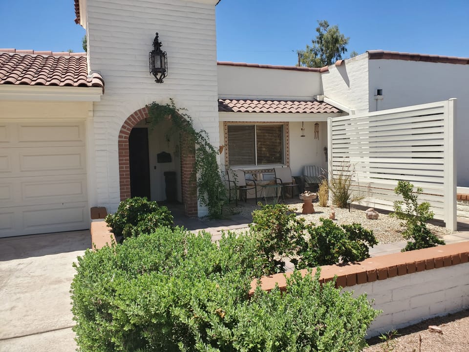 Front of house with courtyard, windows to front bedroom and front entry way.