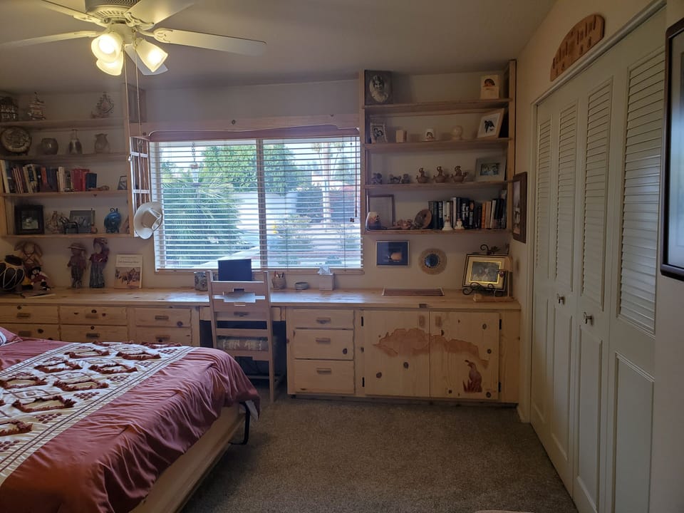 Front bedroom, desk, shelves and view of front yard.
