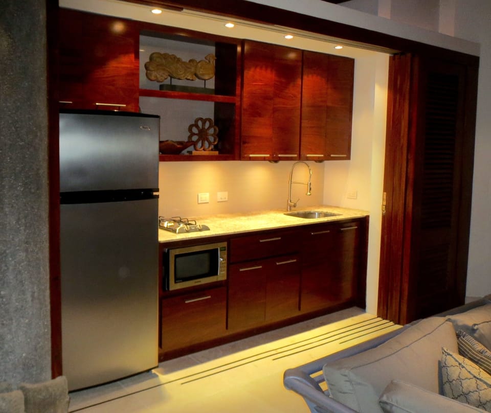 A wall of rich wood louvers doors slide away to provide you with a small kitchen