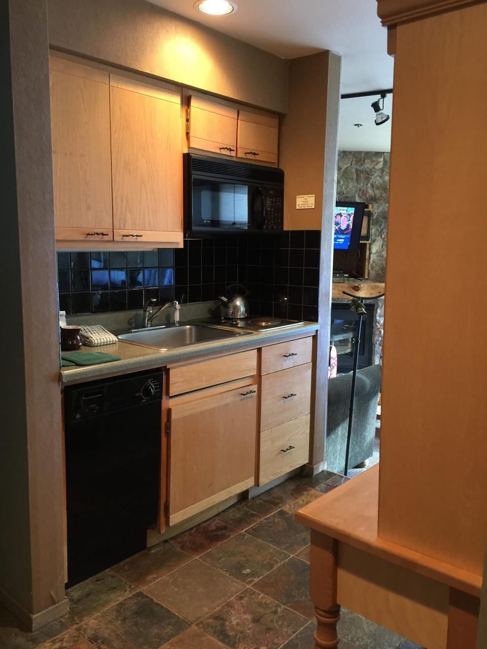 Galley kitchen with two burner cook top, small dishwasher, and a full size frig.