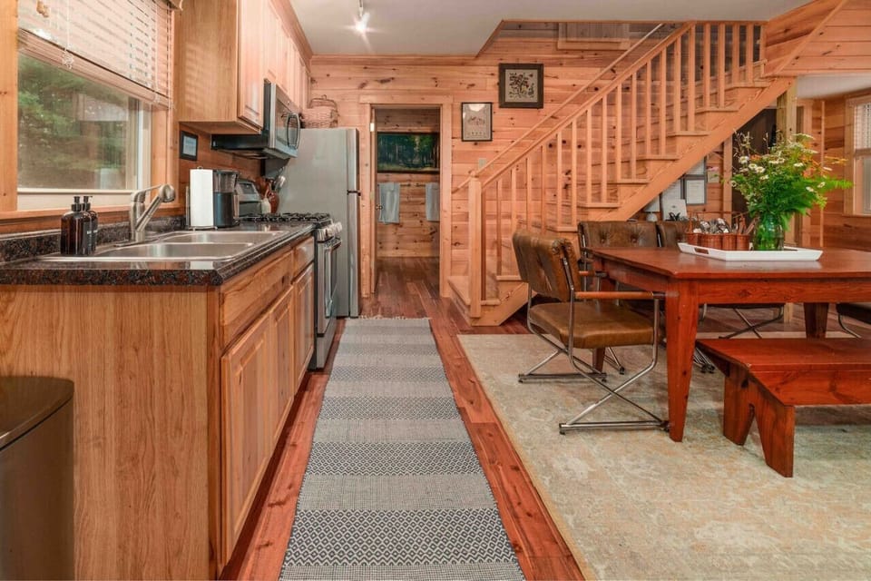View from kitchen area to full bathroom and stairs leading to second bedroom and sleeping loft.
