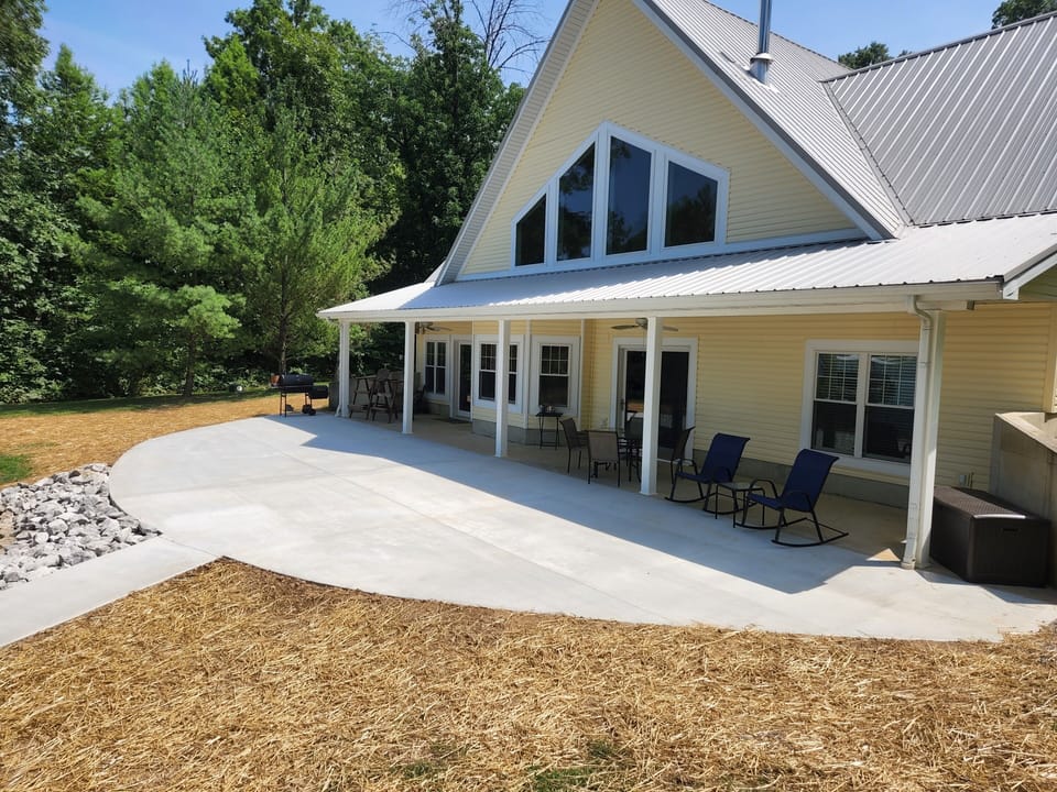 Covered porch with outdoor table, grill, and seating. 