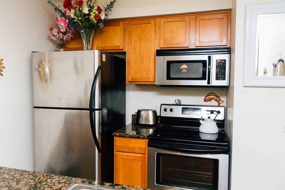 KITCHEN WITH FULL SIZE FRIDGE AND STAINLESS STEEL APPLIANCES
