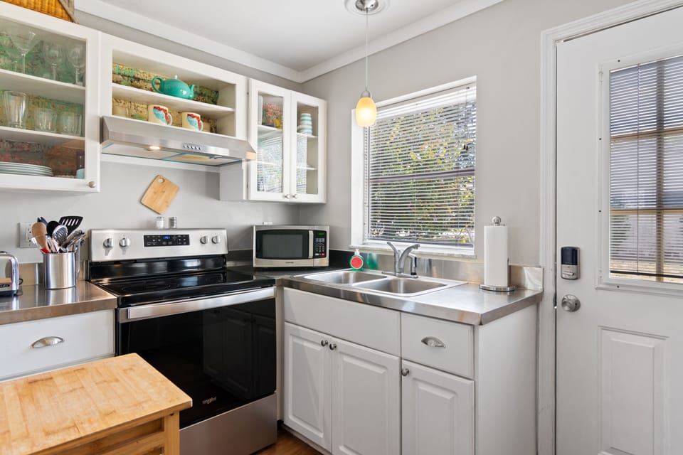 Complete kitchen with nice dishes, silverware, cookware and utensils.\