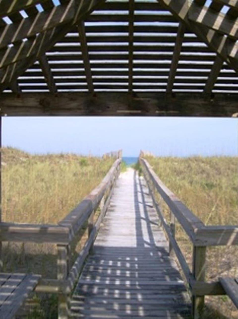 Walkway to beach with bench and cover.
