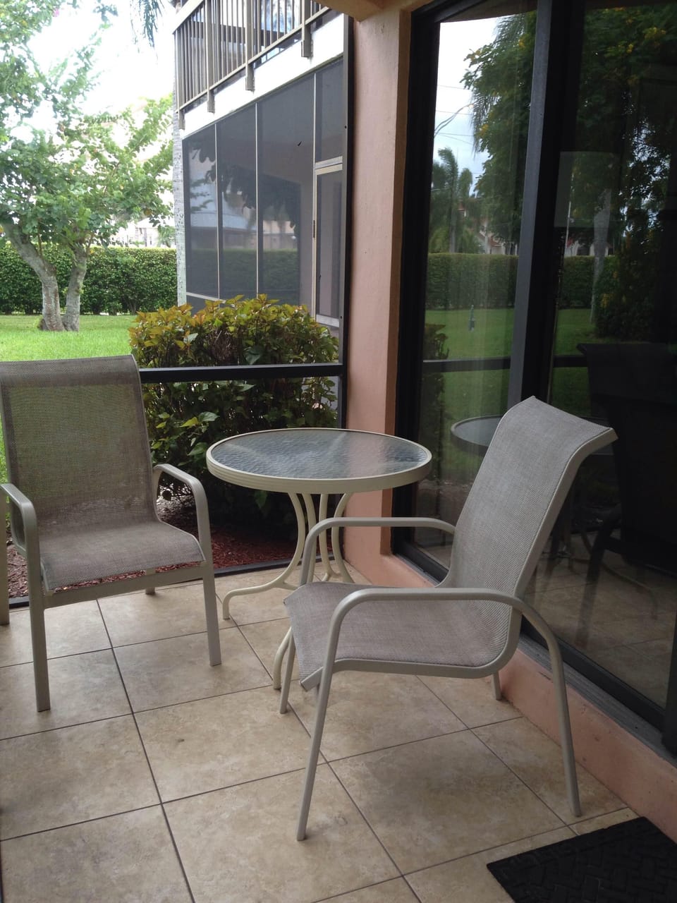 Screened lanai has seating for four and looks onto relaxing landscape