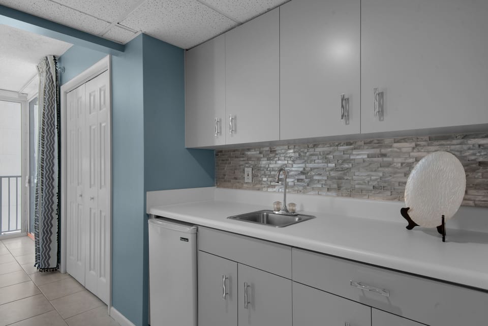 Small refrigerator and sink with additional cabinetry storage.