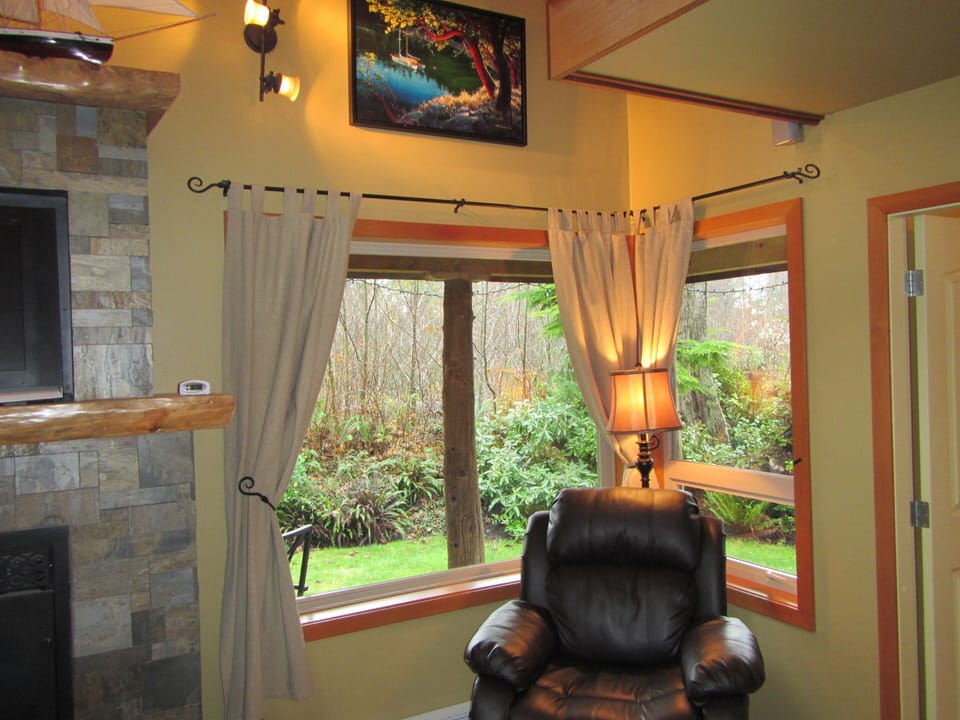 Corner by fireplace with view of front yard during winter time.  Above is a work from Mark Hobson, local artist.
