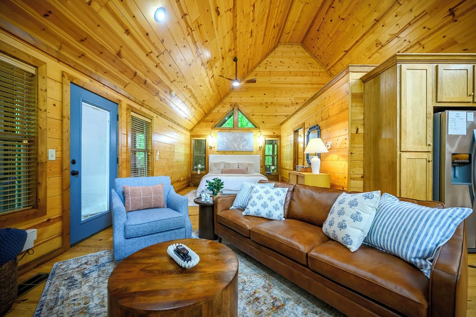 Unwind in your cozy cabin retreat with vaulted wood ceilings, plush leather seating, and a bedroom just steps away, blending rustic charm with modern comfort.