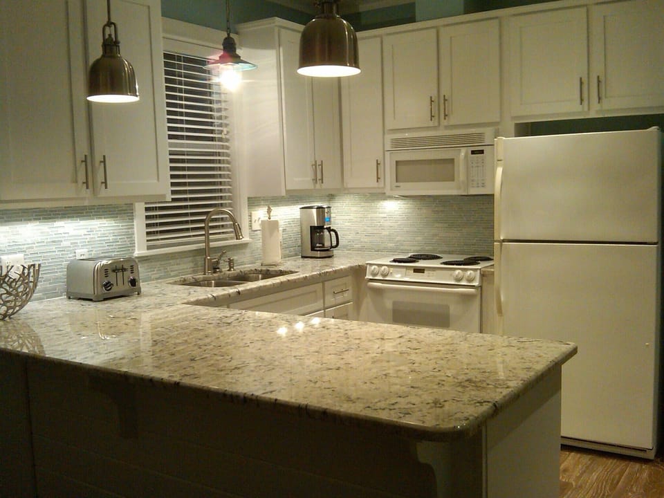 Remodeled kitchen with granite and glass backsplash.