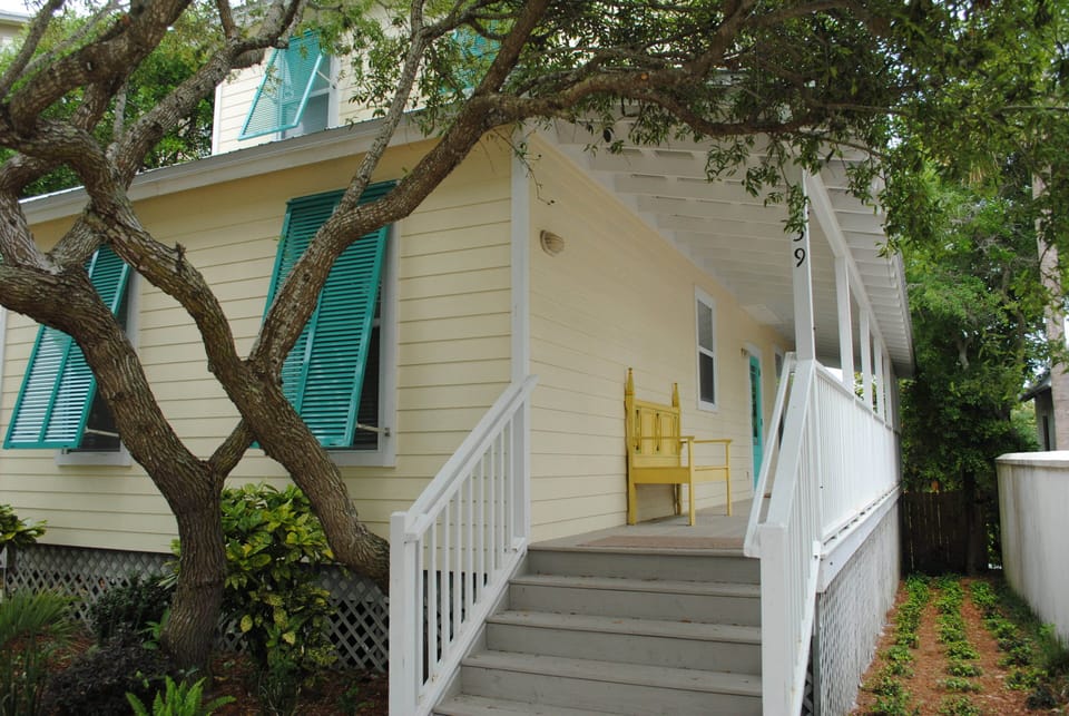 Deck wraps around two sides of home; cottage surrounded by estate-like homes.