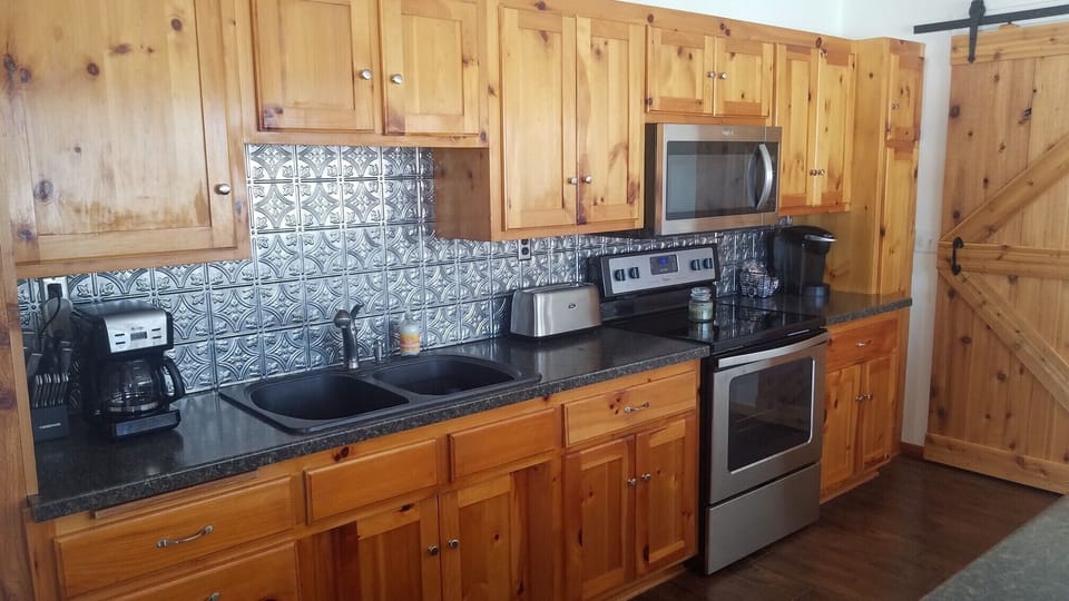 Knotty pine kitchen with a new dishwasher and a barn door lead into the foyer