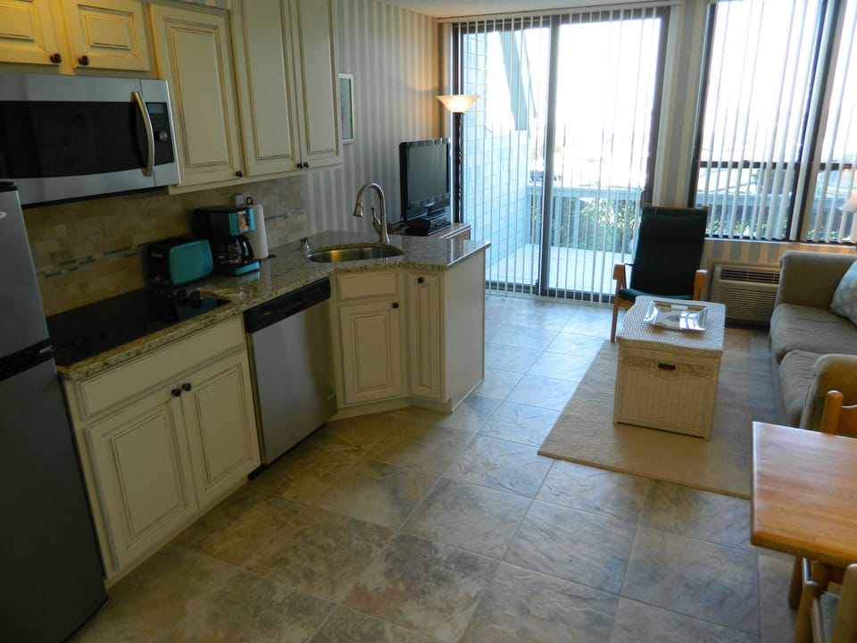 New kitchen & tiled floor with views of living room & slider to private deck