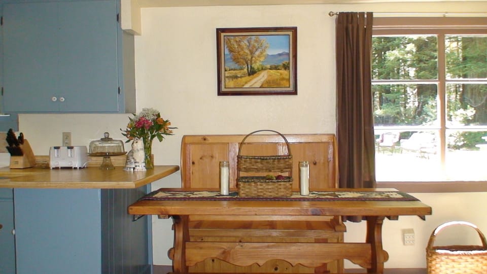 Dining area adjacent to kitchen with antique pine tressel table and benches
