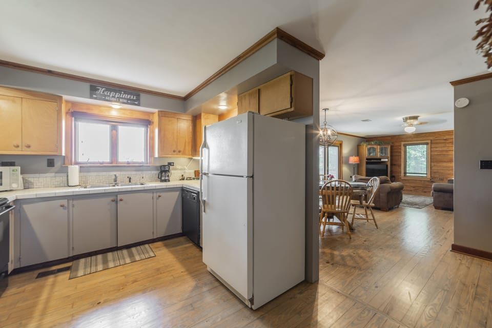Full kitchen with cooking utensils, small appliances, pots/pans, & dishes.