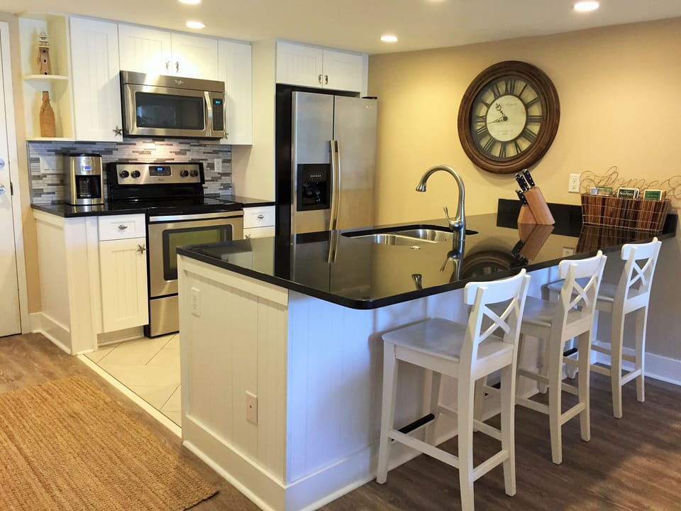 Brand-new kitchen and appliances with large granite bar and three bar stools