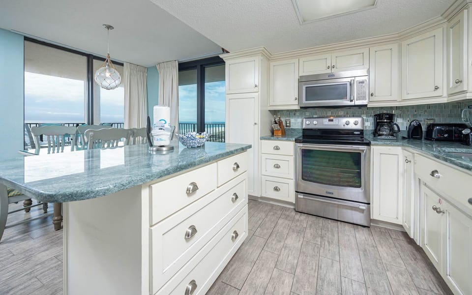 Prepare meals around the island in a kitchen that features stylish cabinetry, stainless appliances, and an elegant design