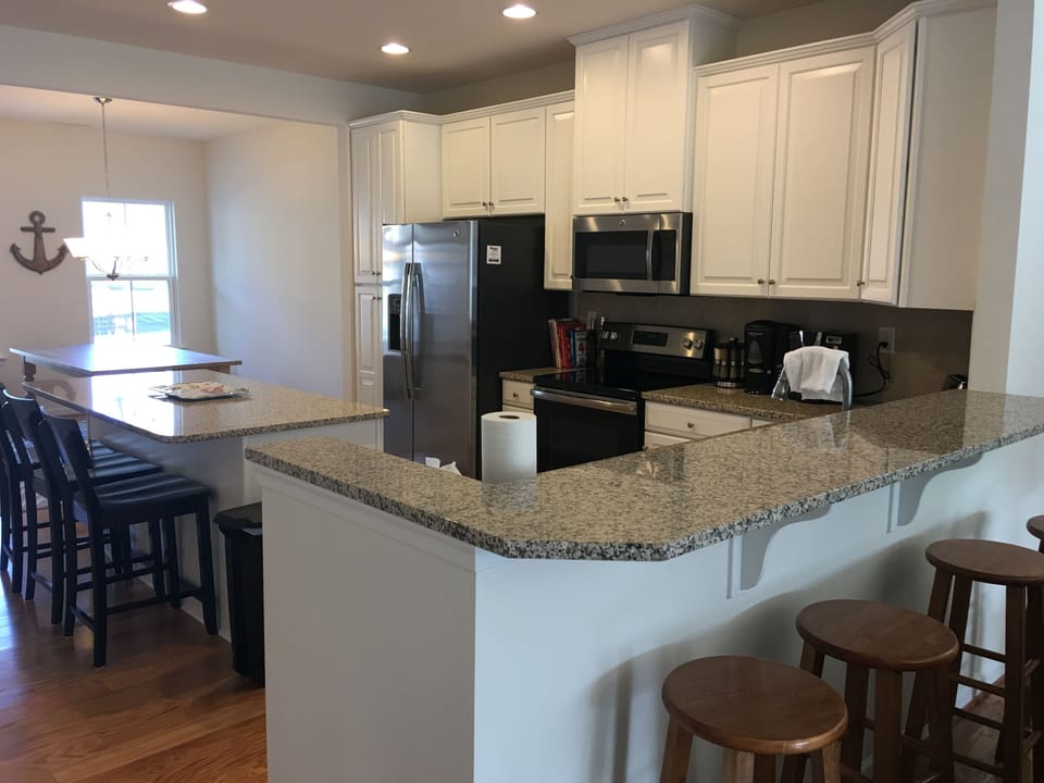 Fully stocked kitchen with granite counters and stainless steel appliances.