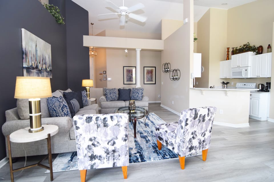 Stylish living area with new sofas, arm chairs, ceiling fan, Smart TV
