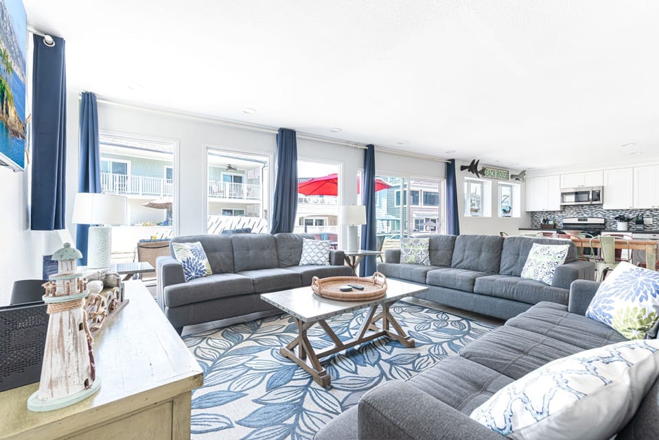 The main living area includes a sofa/loveseat set, side seating, cable TV, and a sliding glass door that opens to expansive front oceanview patio.
                