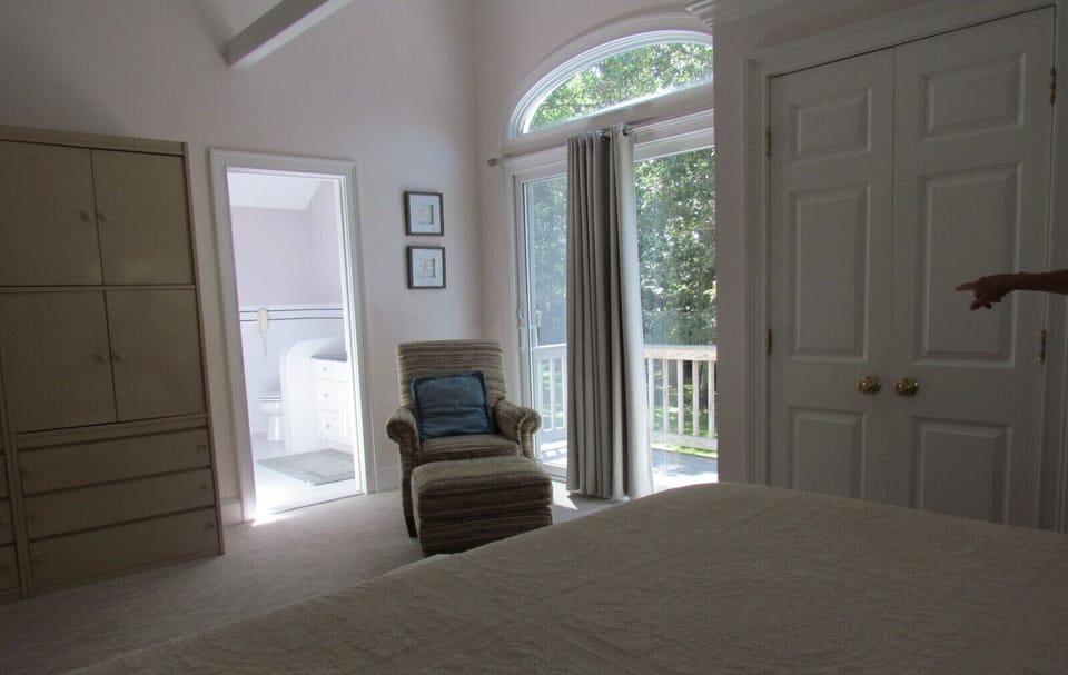 other side of master bedroom with bench, chair, private balcony and bathroom