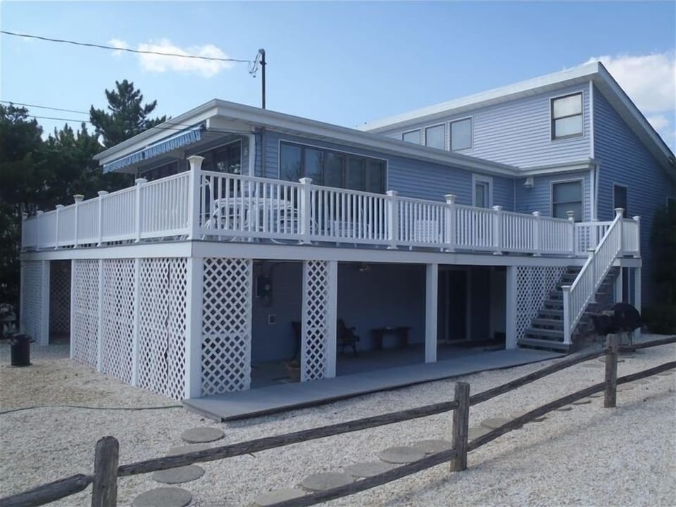 Side photo of the house. Deck wrap around.  Gas grill next to stairs.