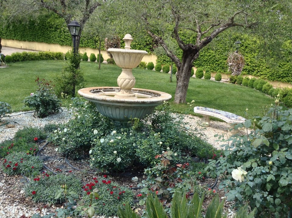 Water fountain feature next to garden area. 