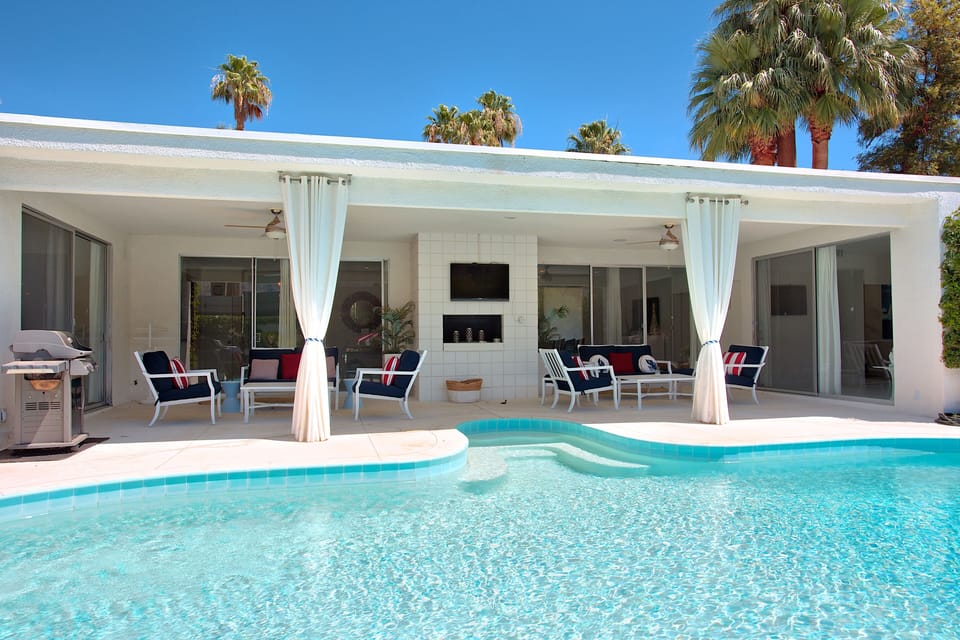 Fireplace and patio seating with shaded pool area.