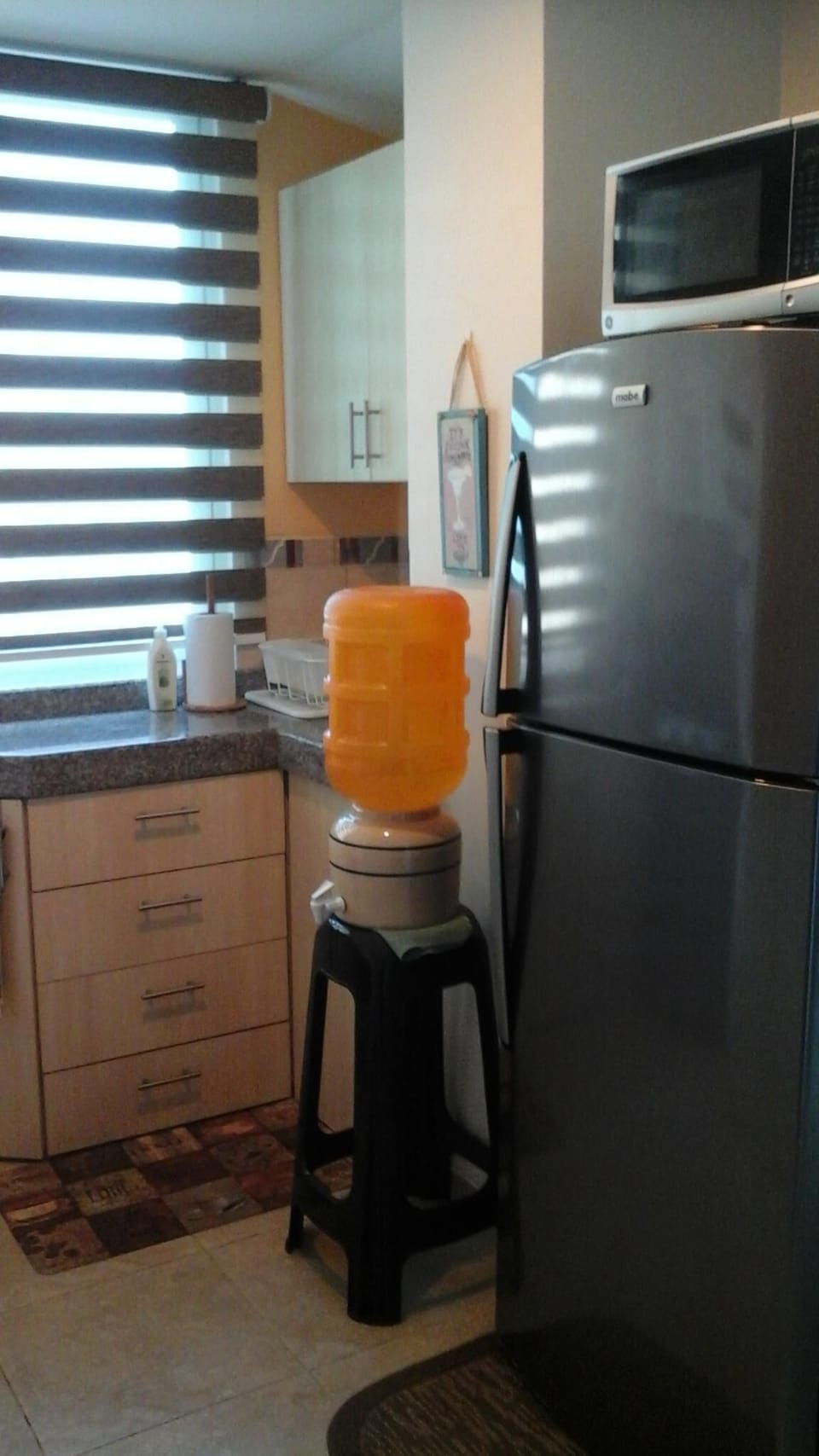 Kitchen area with  refrigerator, microwave and water stand for drinking wate