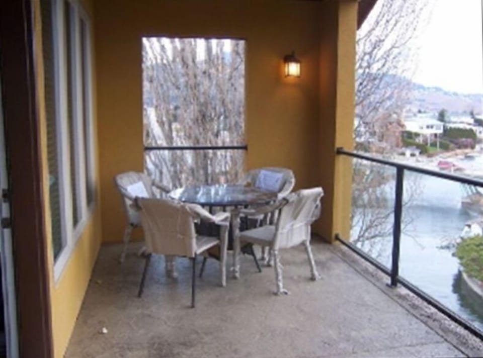 Covered deck off living room with view of canal and Lake Okanagan