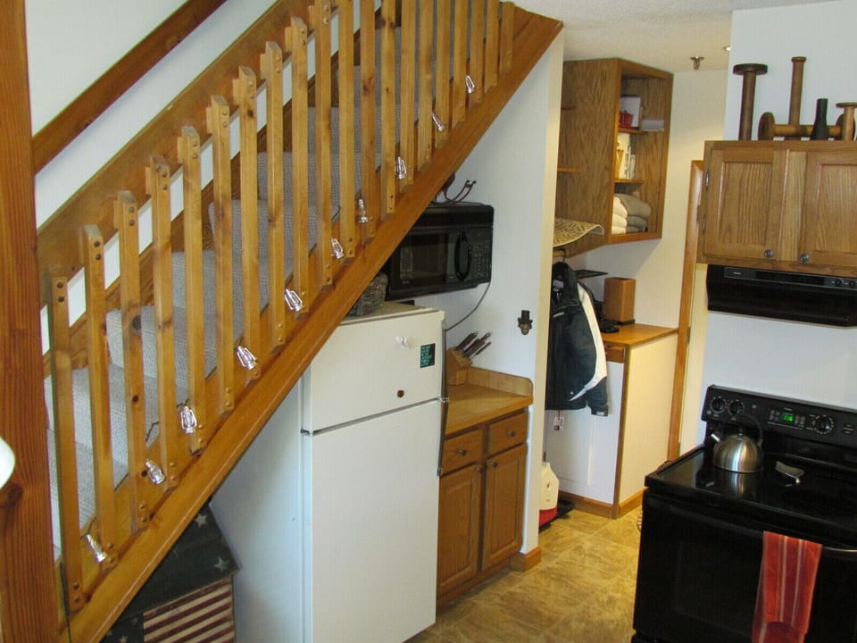 Microwave, fridge, food prep area, storage shelves and coat hanging area