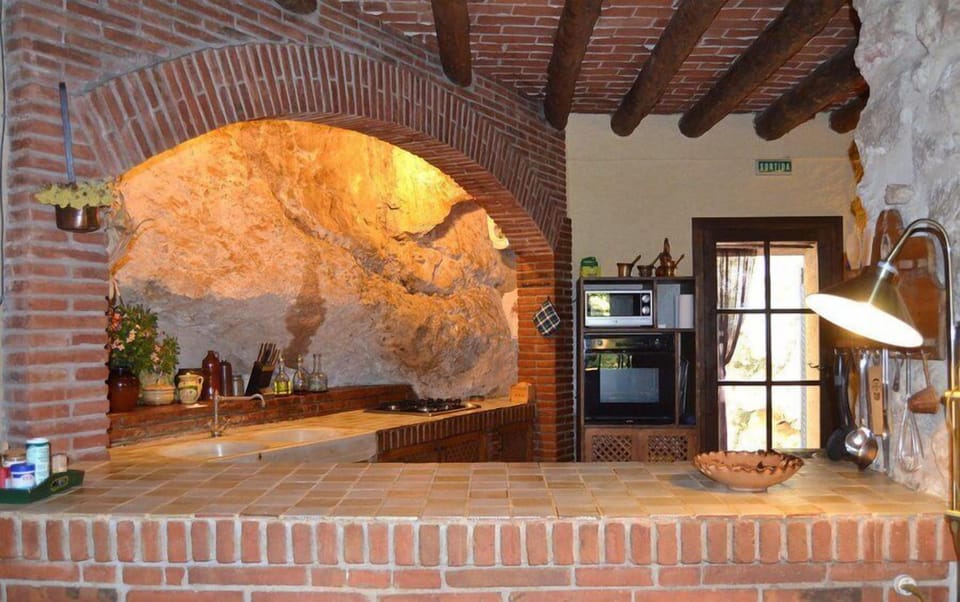 The kitchen is well equipped and surrounded by naked rock and stone walls