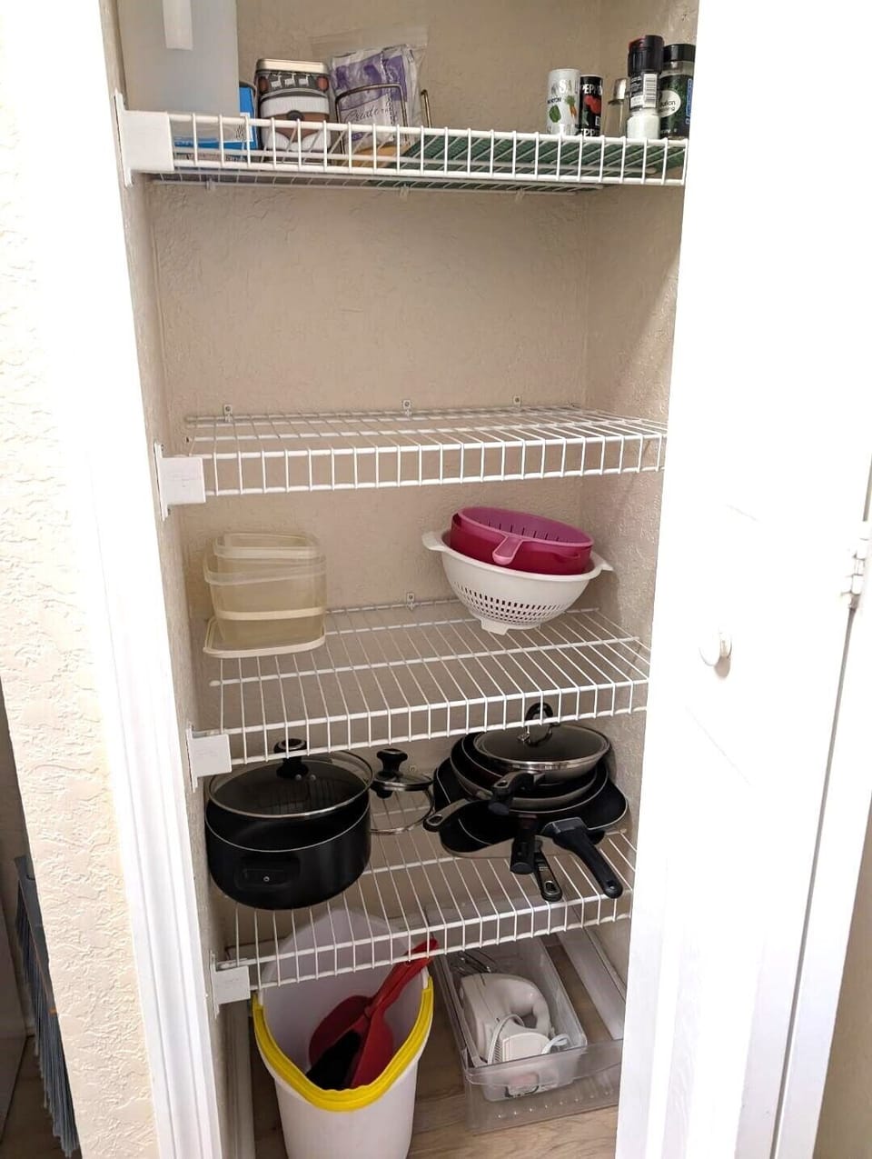 Kitchen closet with frying pans, 2 griddles, large pot, electric hand mixer