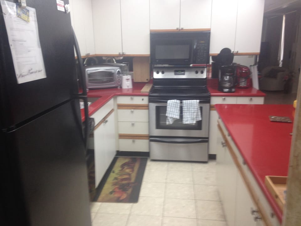 fully equipped kitchen with red granite countertop.