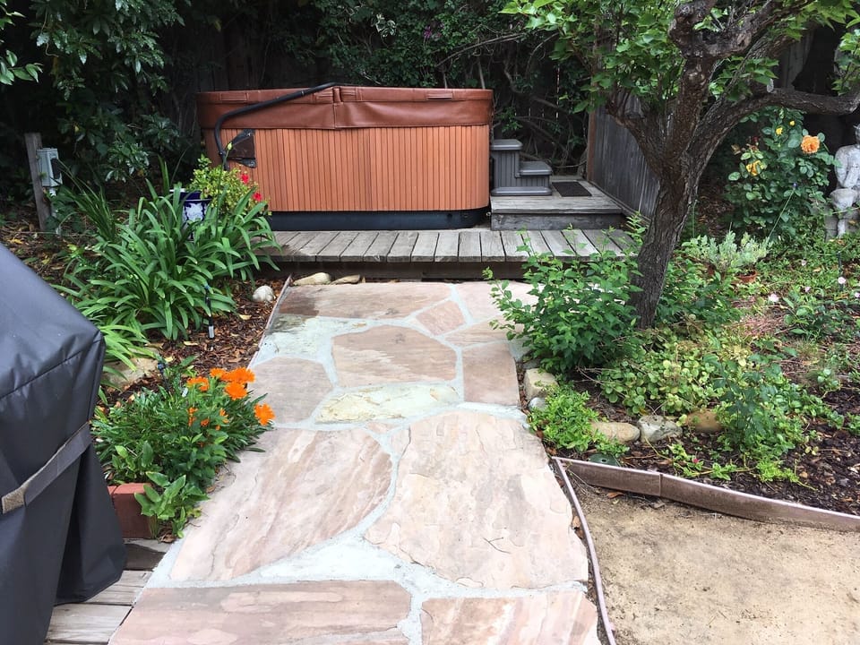 Walkway to hot tub that seats six, edge of gas BBQ  across kitchen doors