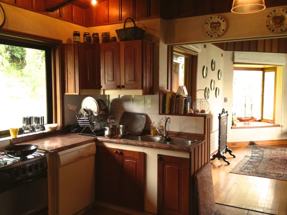 Open-style kitchen with gas range, dishwasher, microwave, fridge & wood stove.