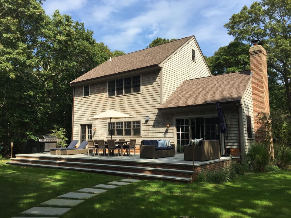 Bluestone patio with teak dining table,  ample seating, outdoor speakers & grill