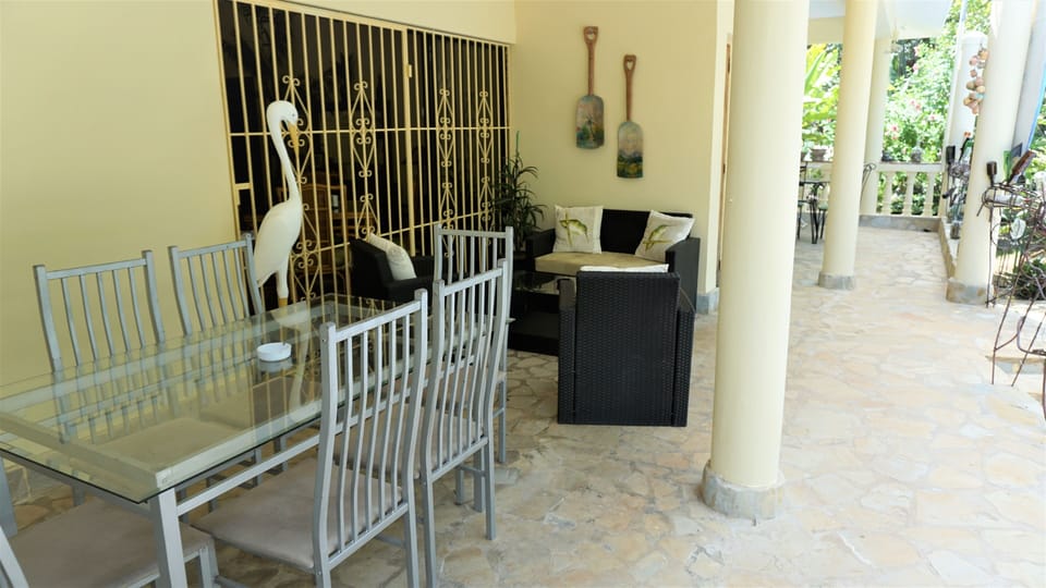 covered terrace with dining and sitting areas next to BBQ