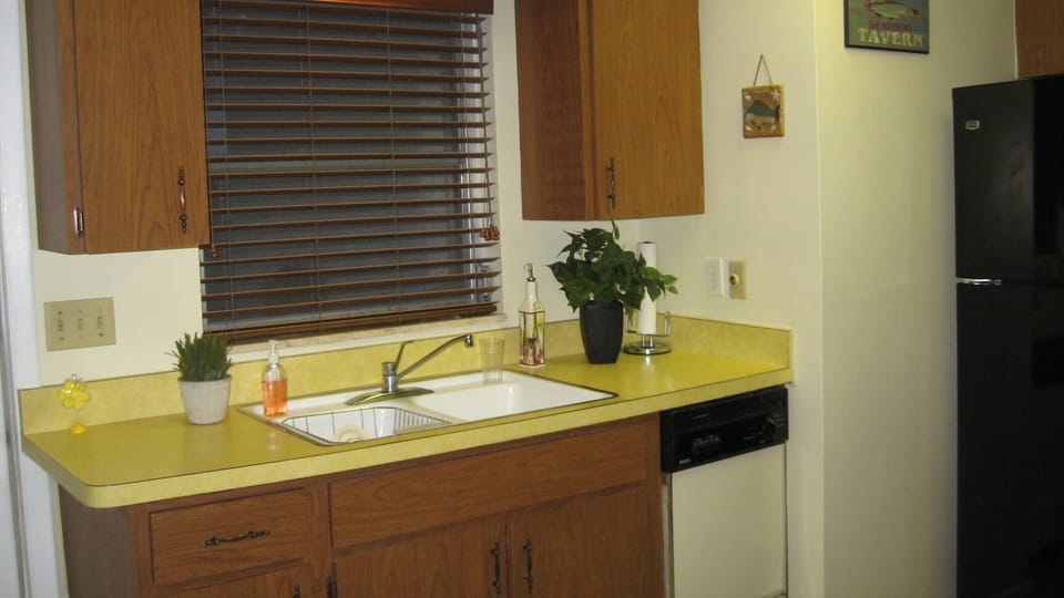 Kitchen window looking out at garden area and patio table & chairs.