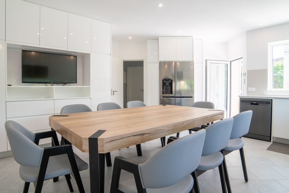 Modern open-plan kitchen and dining area with wooden table — Villa Atlantica, luxury holiday villa in Grândola