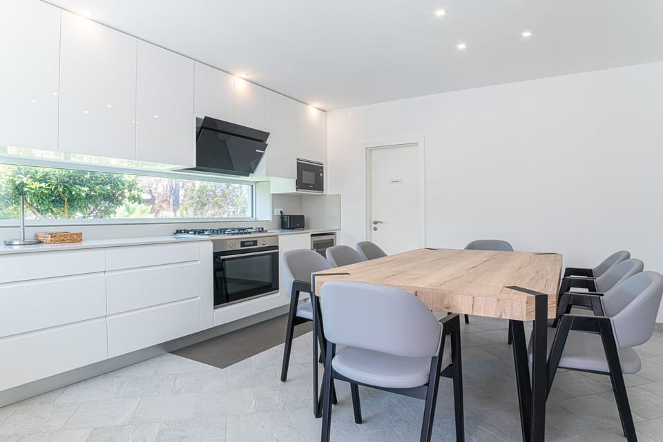 Modern open-plan kitchen and dining area with wooden table — Villa Atlantica, luxury holiday villa in Grândola