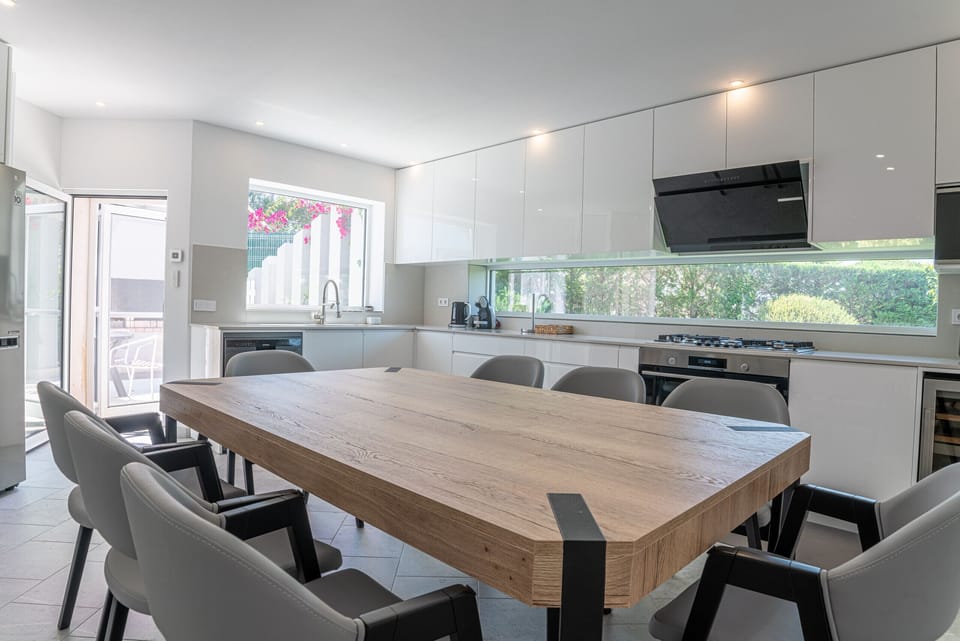 Modern open-plan kitchen and dining area with wooden table — Villa Atlantica, luxury holiday villa in Grândola
