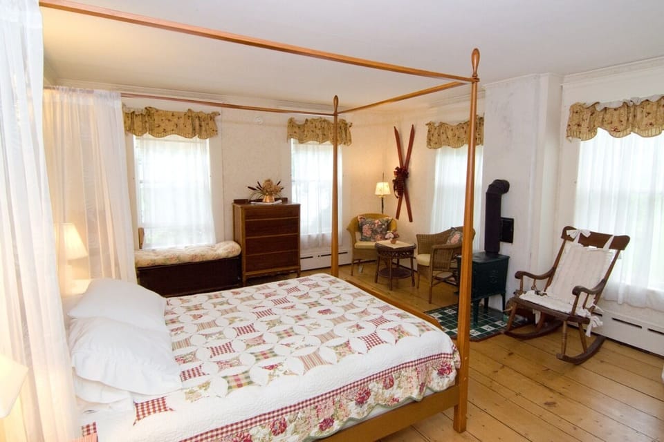 Room 9. A first floor room. This gem has refinished wide pine floors, big windows and a green enamel wood stove on a tile hearth. Queen canopy frame bed and a lovely antique renovated bath with wainscoted walls. TV.  An additional pull-out cot is available for a child.