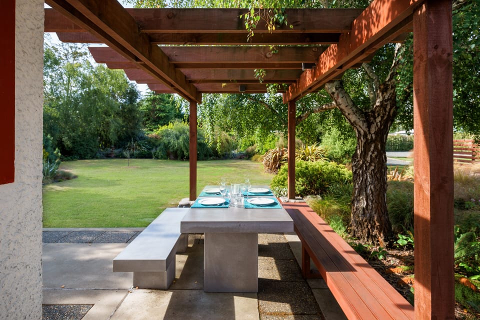 Outdoor seating under pergola overlooking the landscaped garden.
