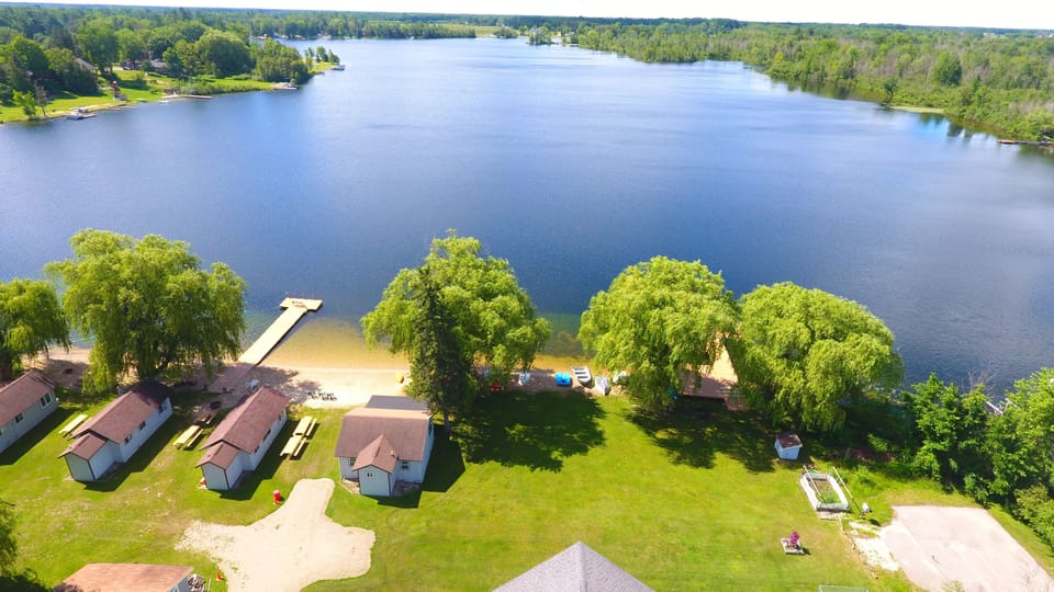 Lakefront cabin showing the sandy beach and swim dock.
