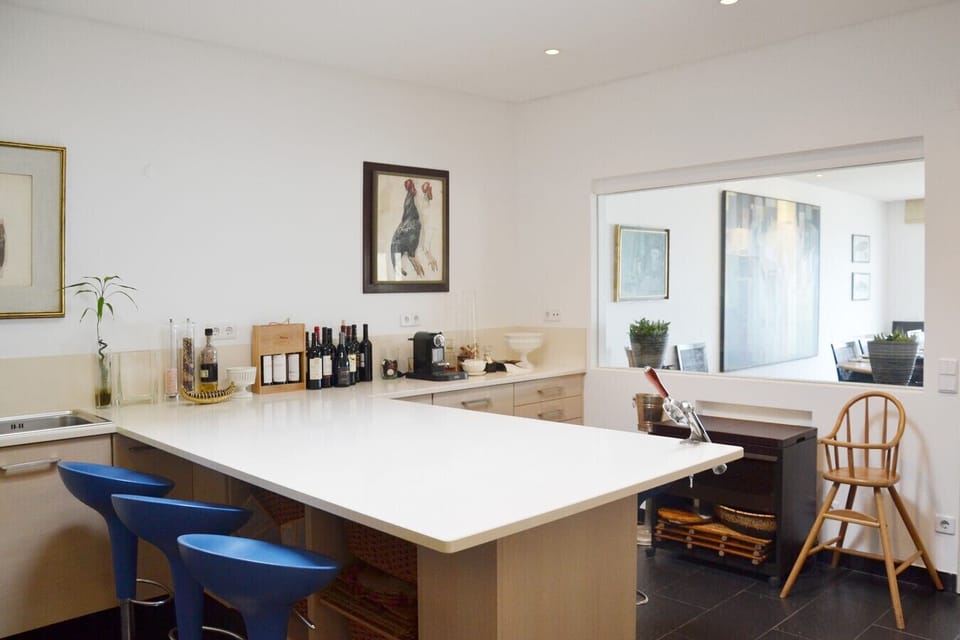 Modern kitchen with white countertop island and blue bar stools — Villa Isis, holiday villa in Sintra