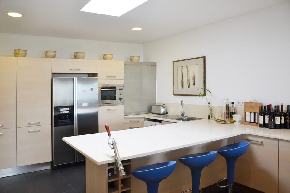 Modern kitchen with white cabinetry and blue bar stools — Villa Isis, holiday villa in Sintra