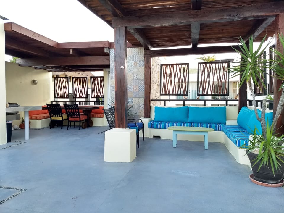 Wide angle view of the roof deck showing living room, kitchen and pergolas