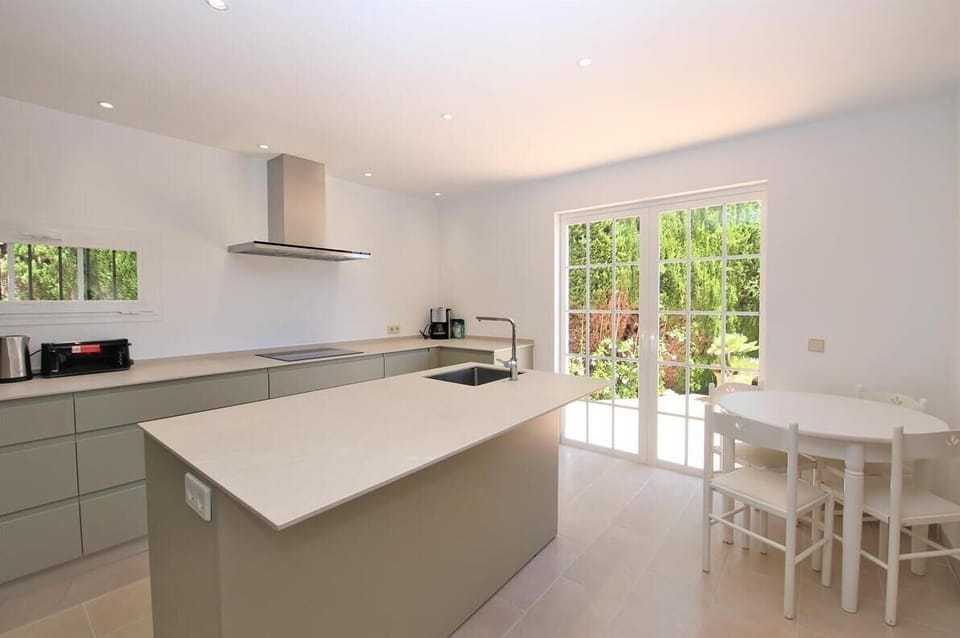 Another view of the kitchen with kitchen island and dining table for four guests