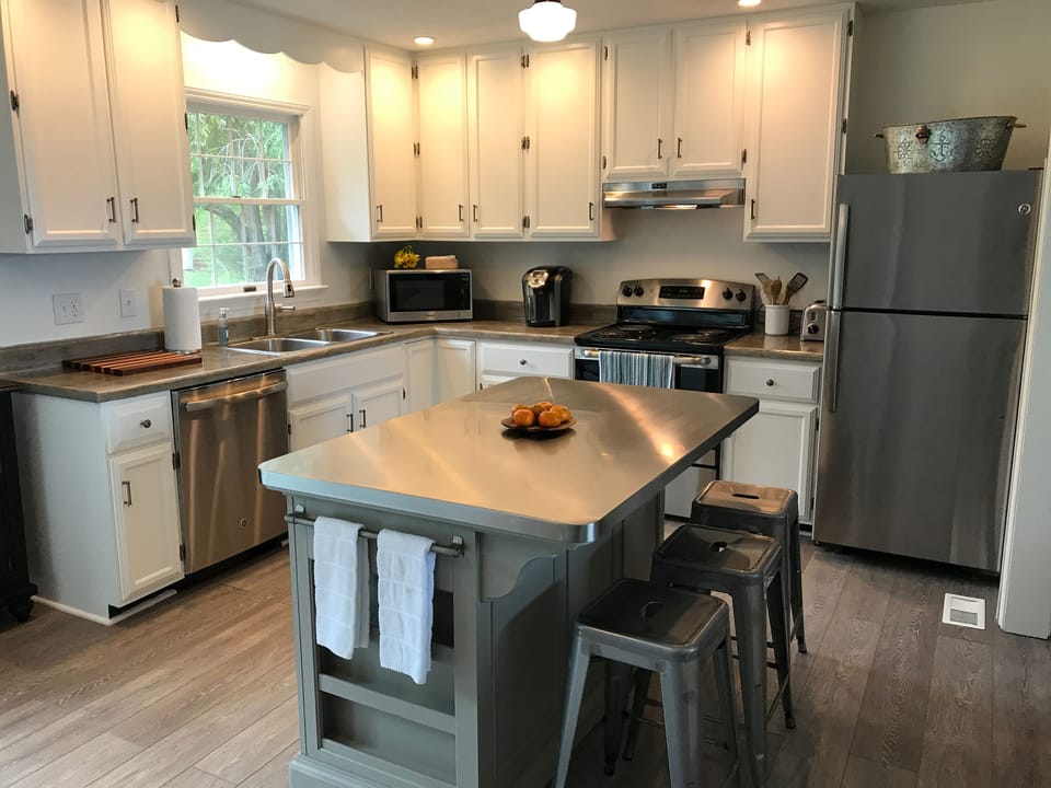Well-lit kitchen with new stainless appliances and convenient island.